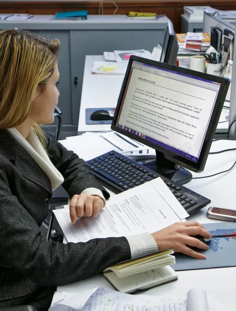 Professional reviewing website copy and documents on a computer in a modern office.