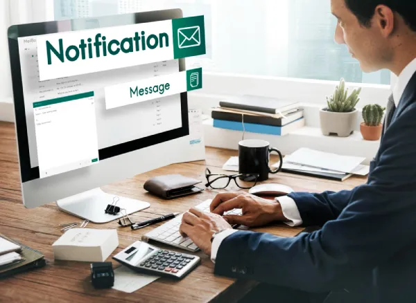 Business professional at a desk with notification and message overlays on a computer monitor.