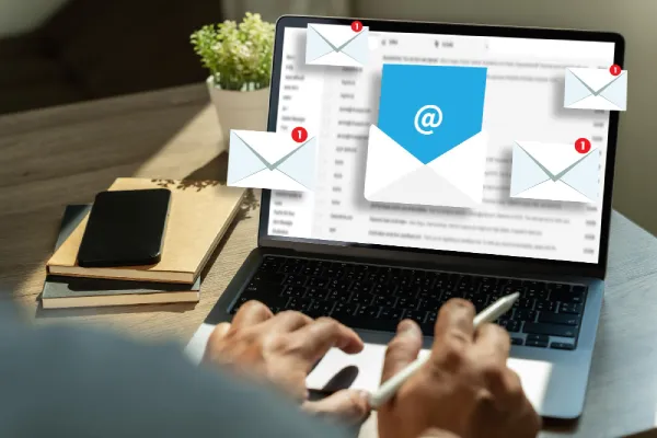 Hands working on a laptop with floating email envelope icons and notification badges above the screen.