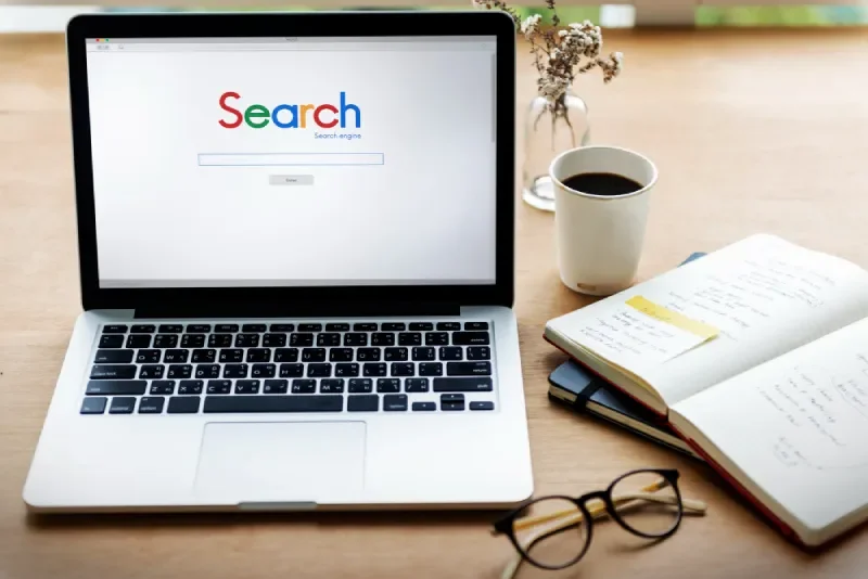 Laptop on desk showing a search engine interface for Google Search Ads campaign planning.