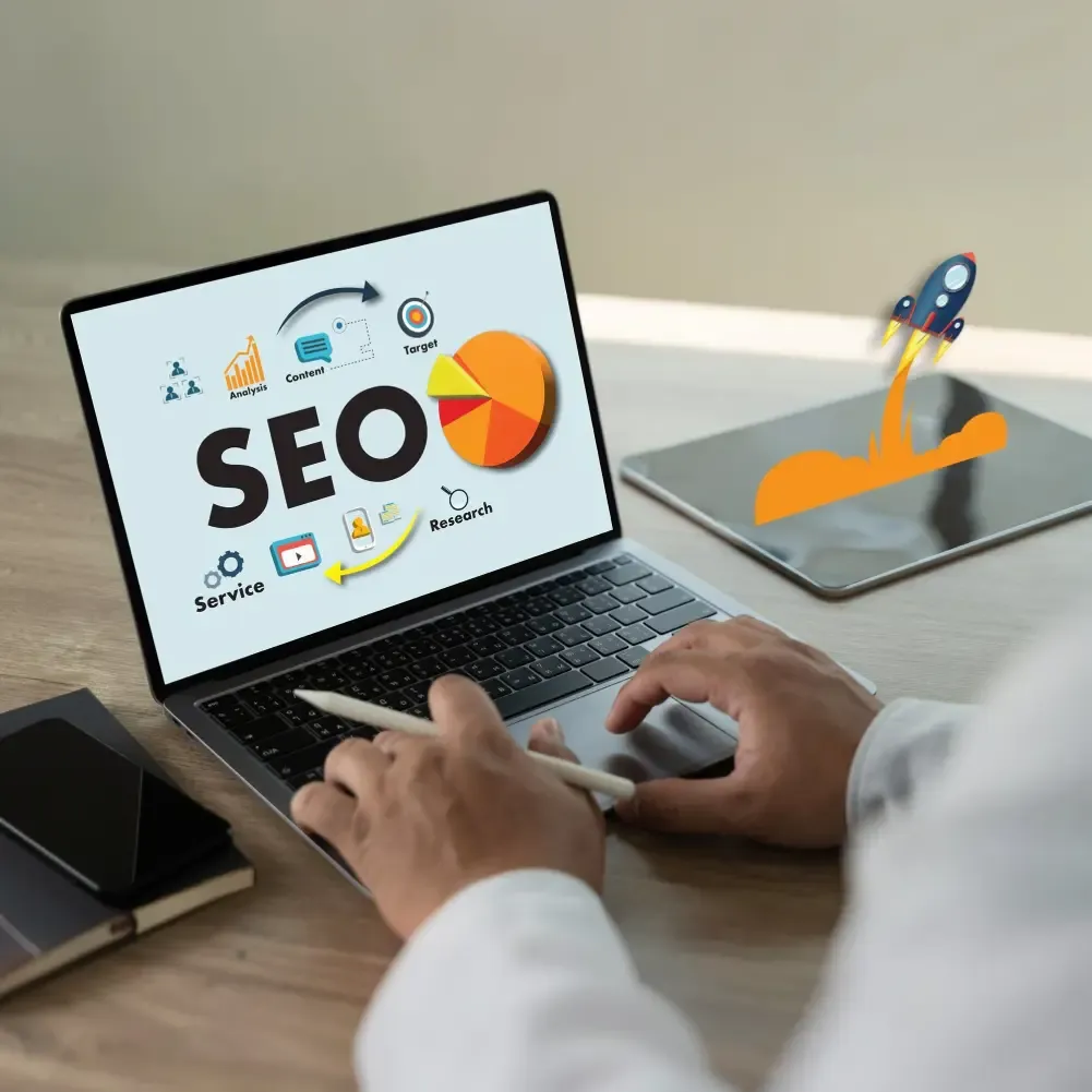 Laptop on a desk displaying an SEO infographic with search optimisation icons on screen.