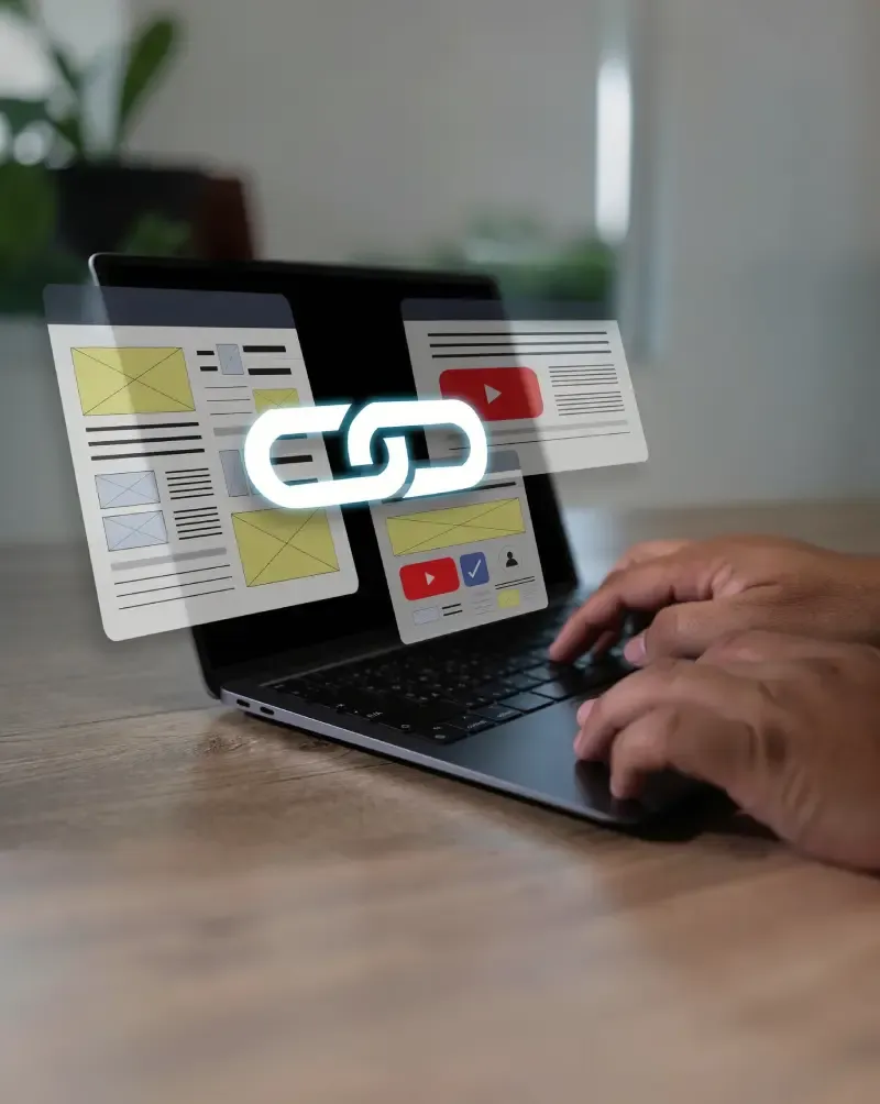 Laptop with hands typing and floating page layouts connected by a chain-link icon.