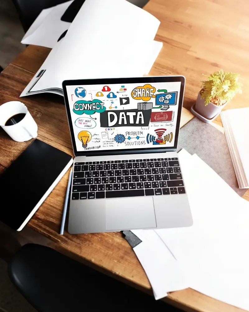 Laptop on a desk showing a hand-drawn DATA infographic with connect, share, and innovation labels.