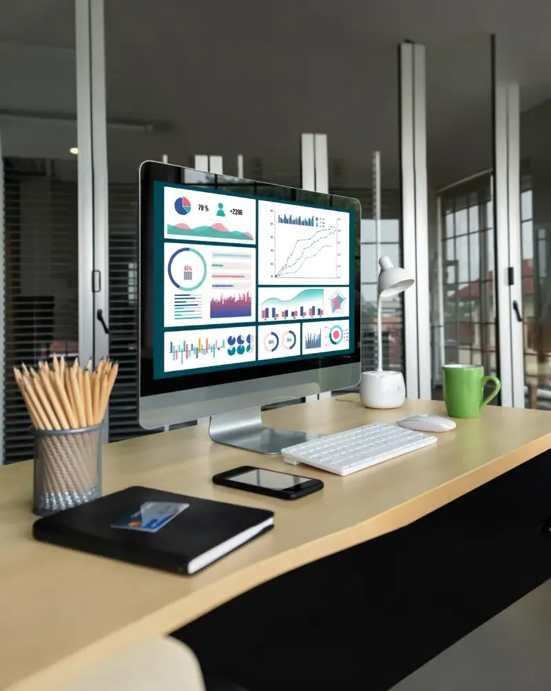 Desktop monitor on a desk showing analytics dashboards with charts and performance metrics.