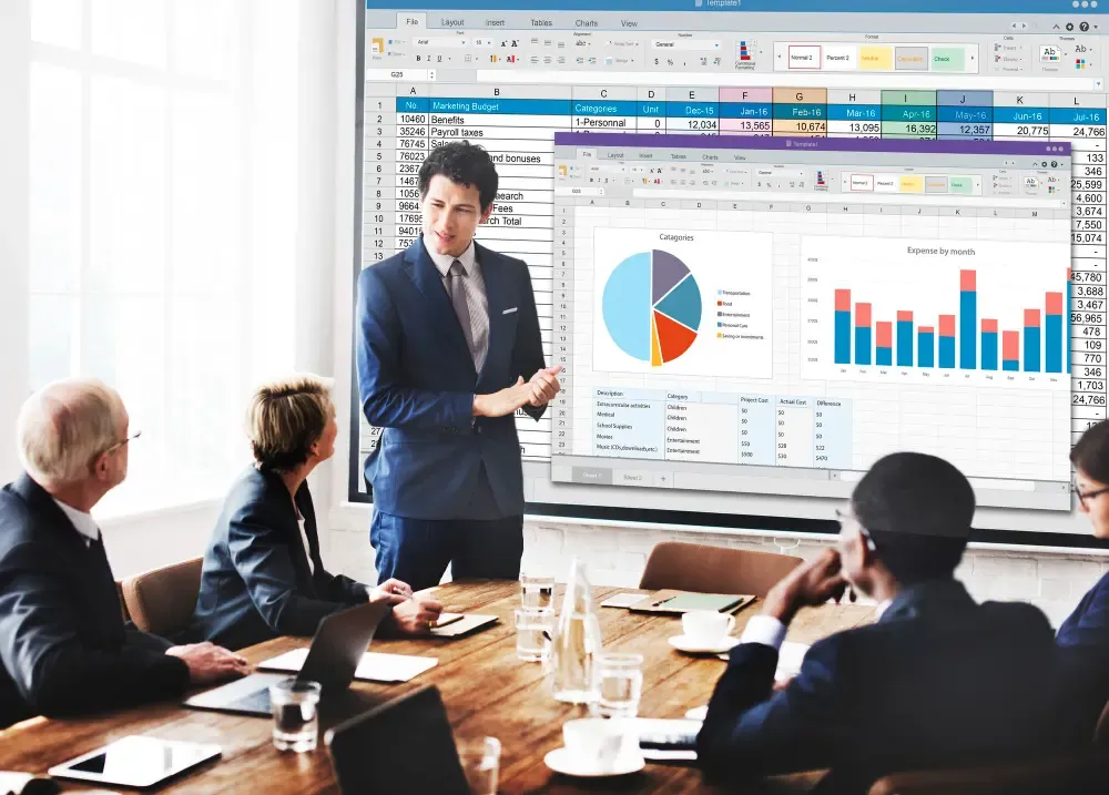 Presenter in a suit explaining marketing budget spreadsheets and charts on a large screen to colleagues seated around a conference table.